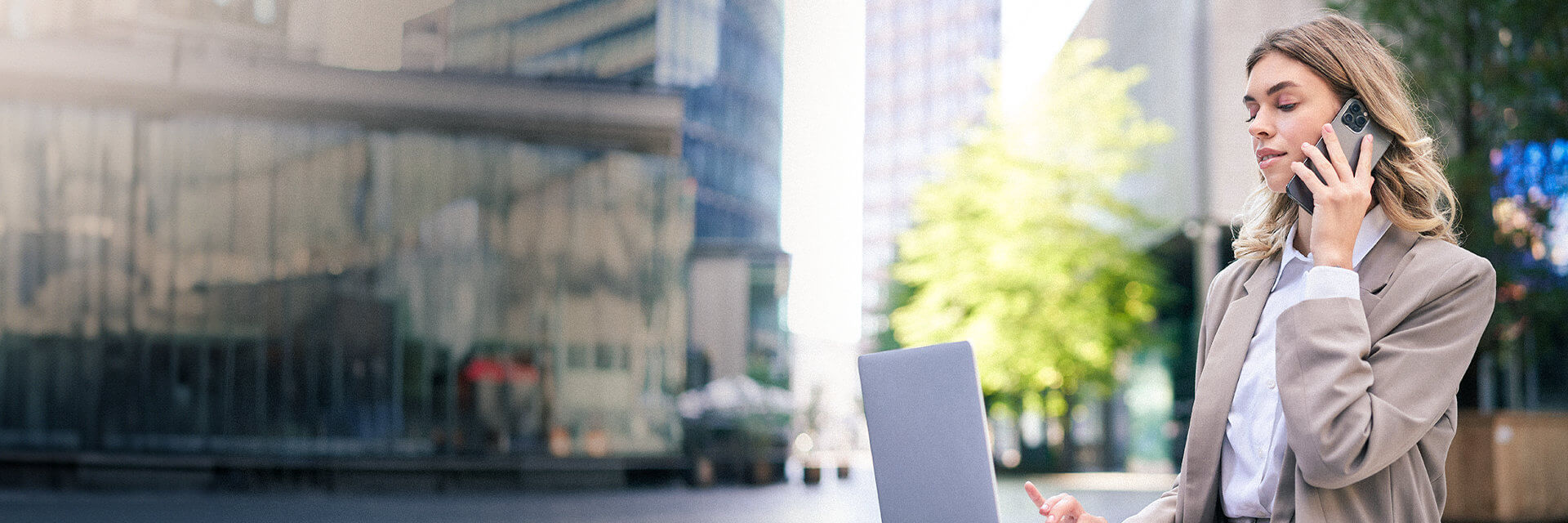 Uma mulher usando um laptop e falando ao celular